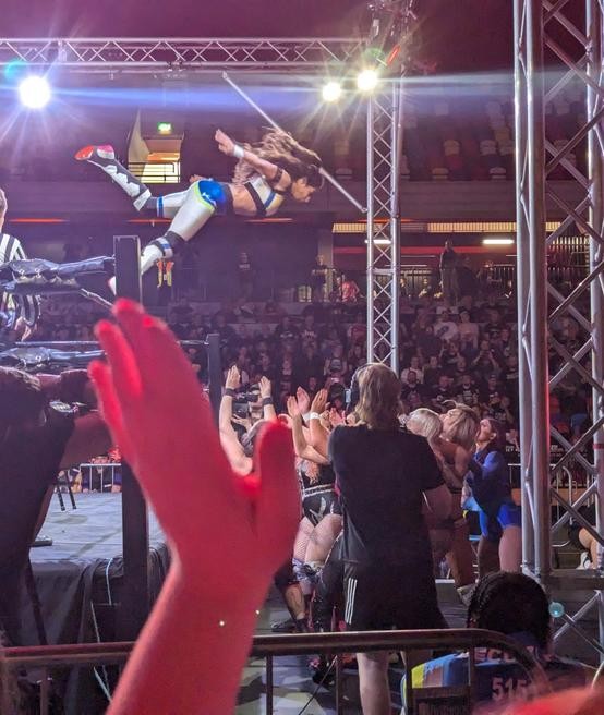 Kanji diving to the outside onto several wrestlers