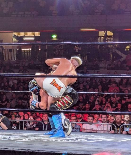 Zack Sabre Jr. wrenching a submission on a doubled-over Hechicero