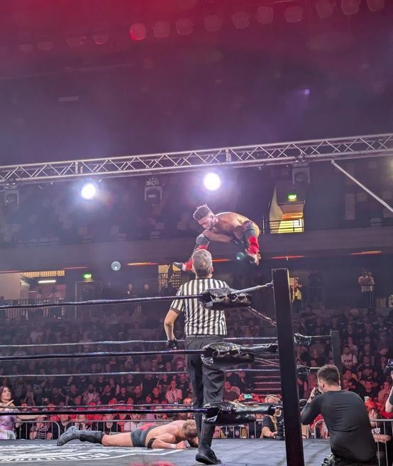 Michael Oku going for a frog-splash from the turnbuckle onto a downed Luke Jacobs